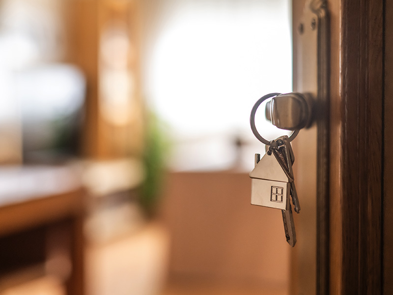 Keys with house charm in the lock of an open front door.